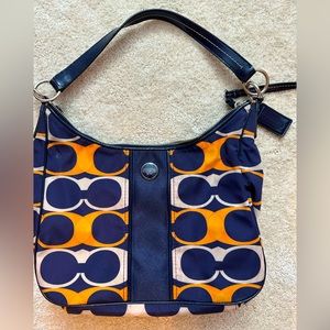 Coach purse, white and orange C’s on navy blue background.
